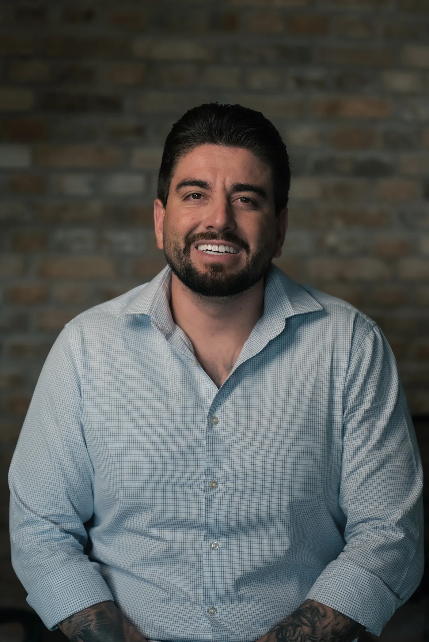Daniel Rodrigues, fundador e CEO do Grupo VR, sorrindo, sentado em frente a uma parede de tijolos