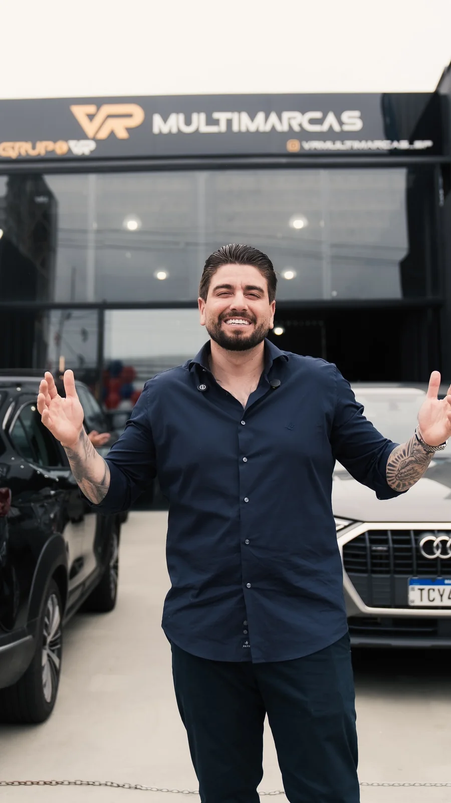 Sócio de braços abertos, sorrindo, em frente à fachada de uma loja VR Multimarcas